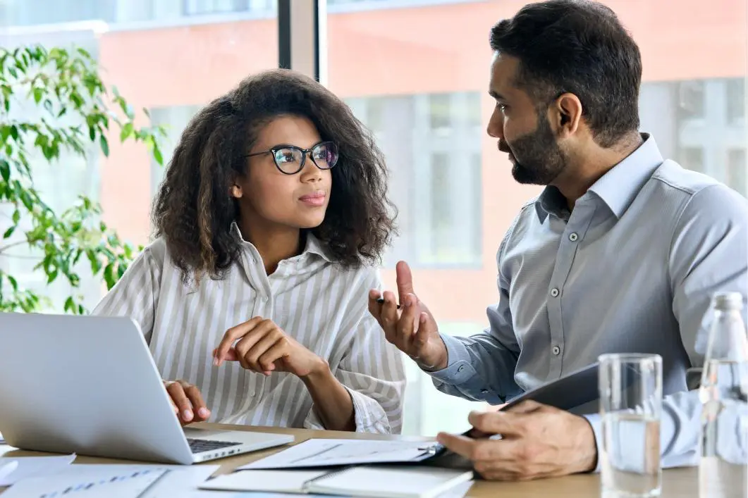 Two colleagues discussing work at a desk.